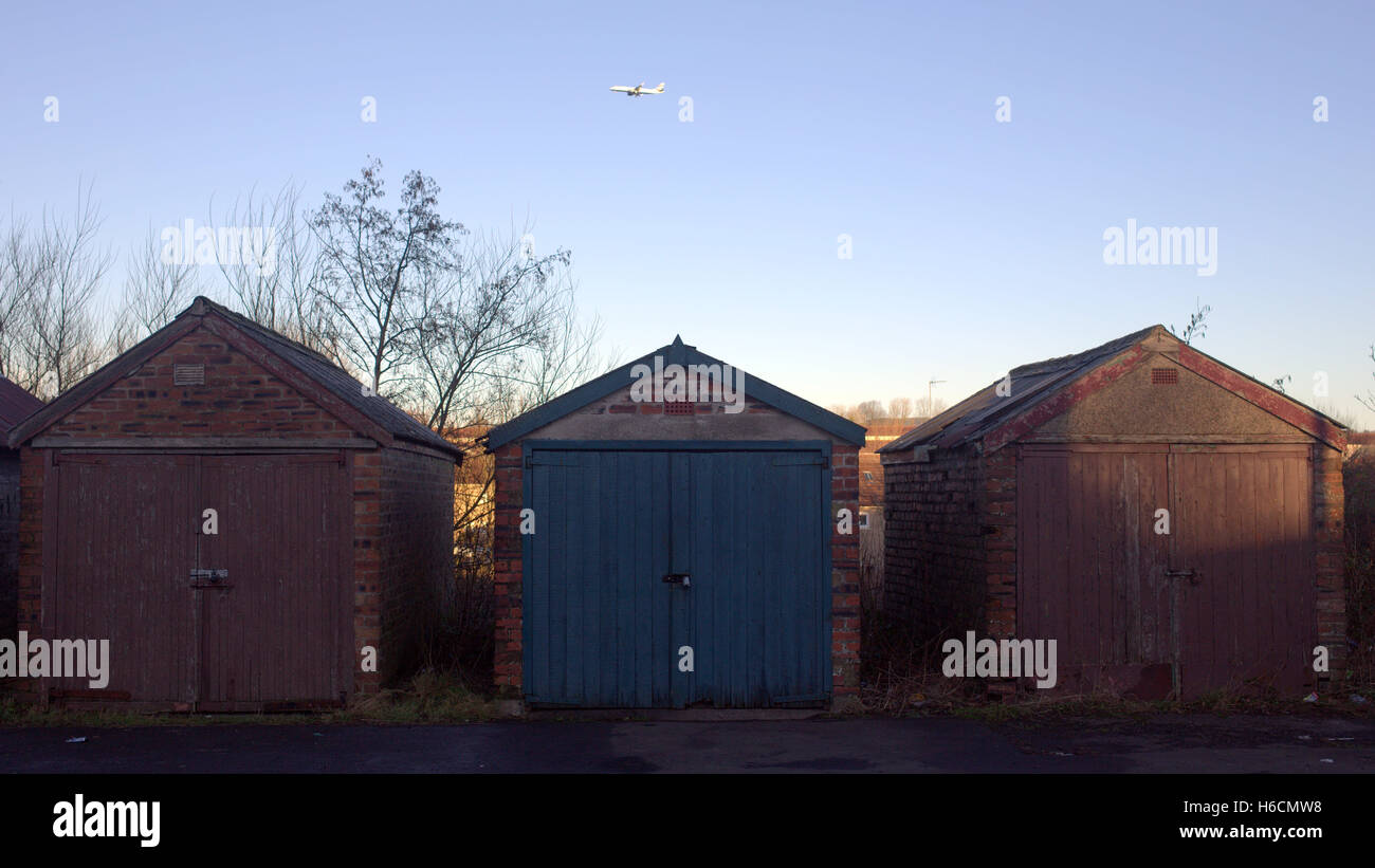 Dilapidated run down sheds still in use with airplane in sky Stock Photo