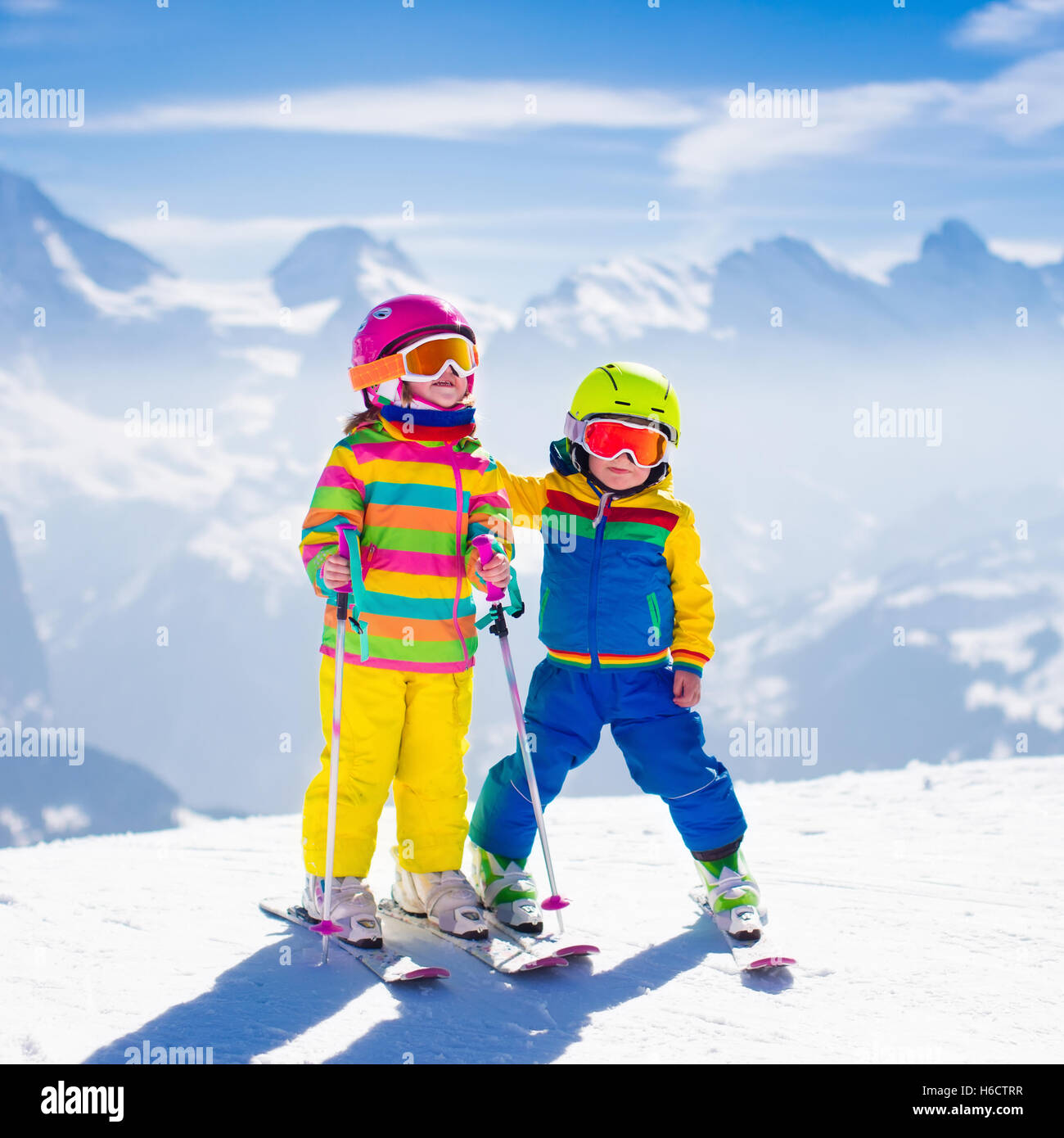 Kids skiing in mountains. Active children with safety helmet, goggles and poles. Ski race for young kids. Winter sport Stock Photo