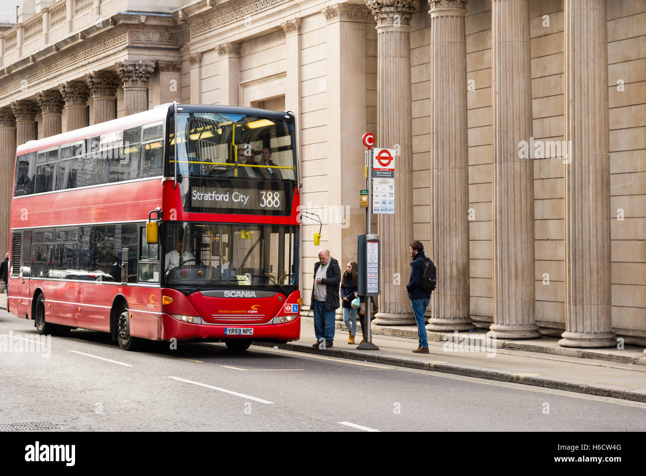 Double-decker London bus at a stop with passengers alighting. Stock Photo