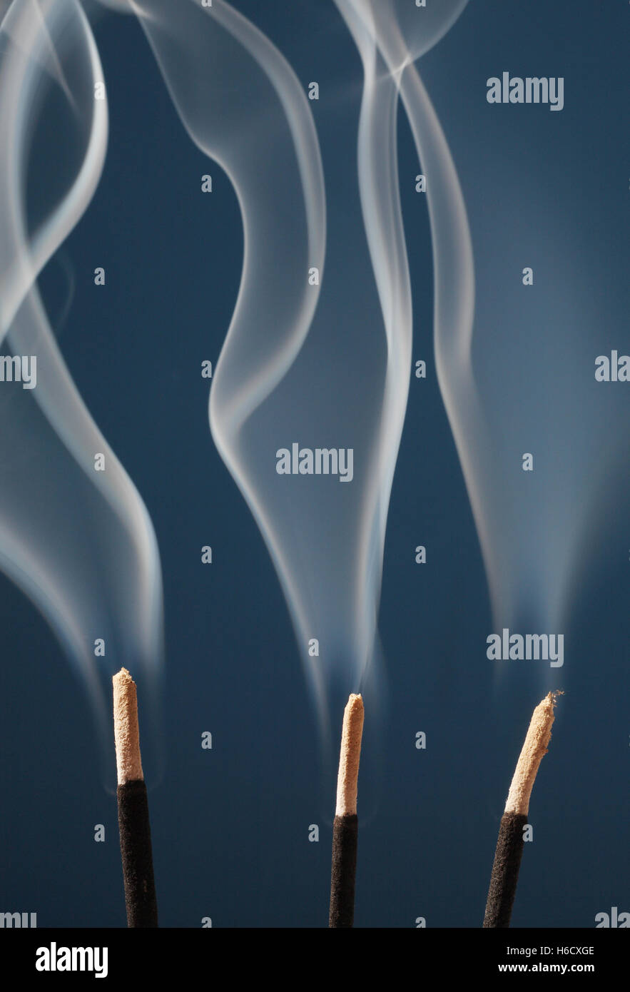 Smoke rising from three incense sticks Stock Photo