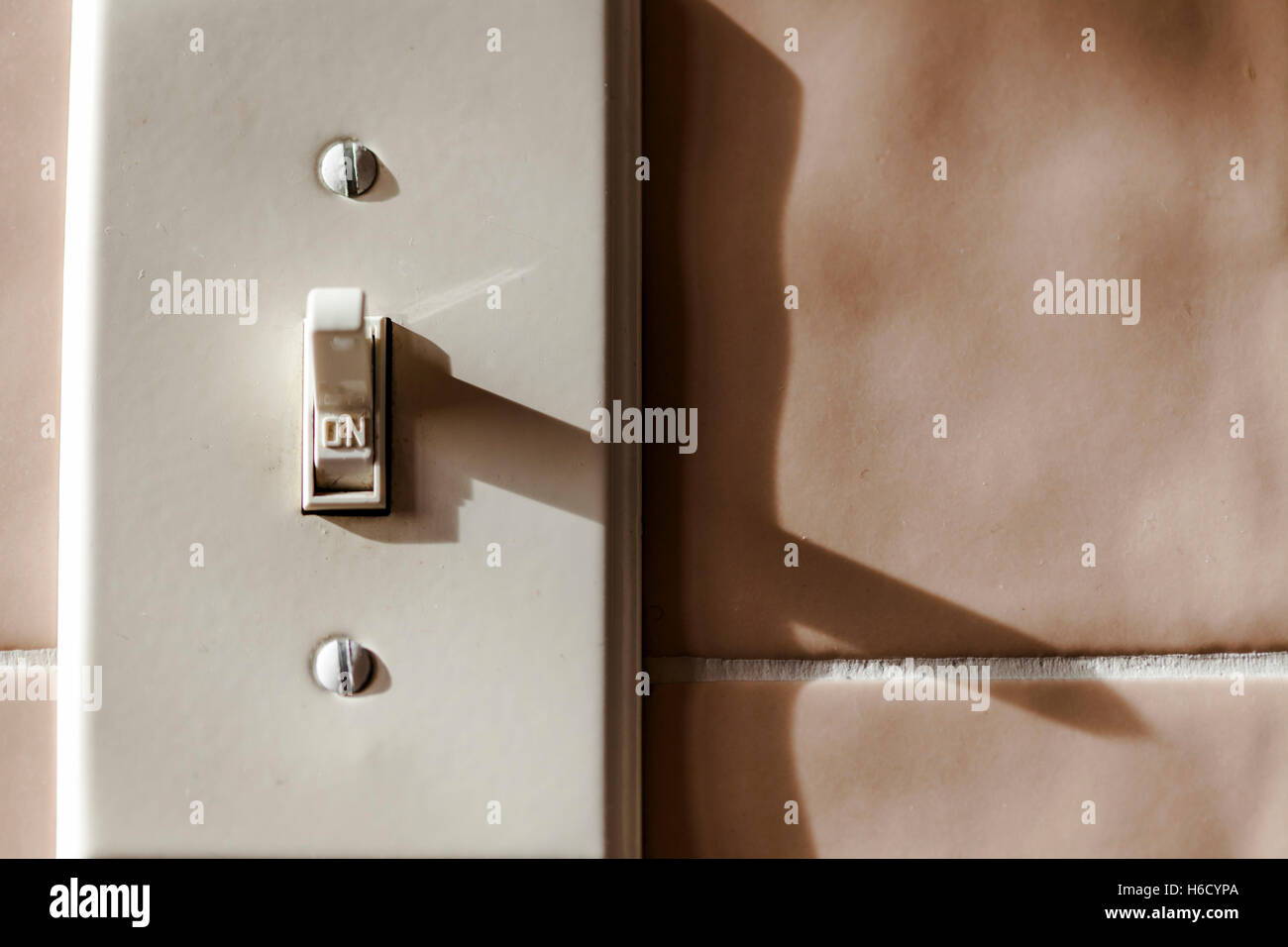 Light switch on tile ceramics wall turned on Stock Photo