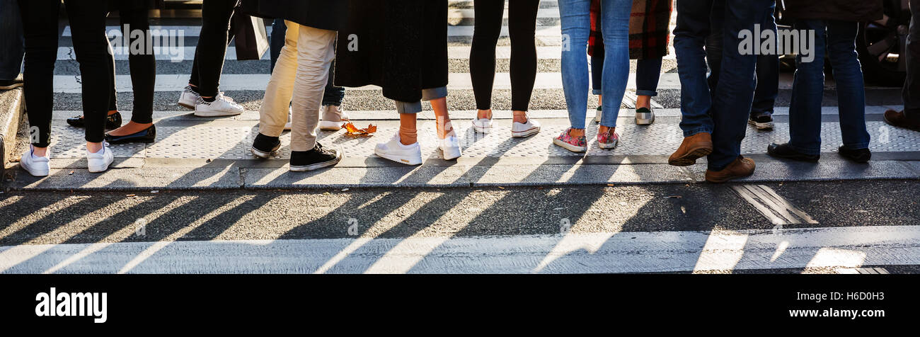 detail of the legs of a crowd of people waiting at the pedestrian crossing Stock Photo