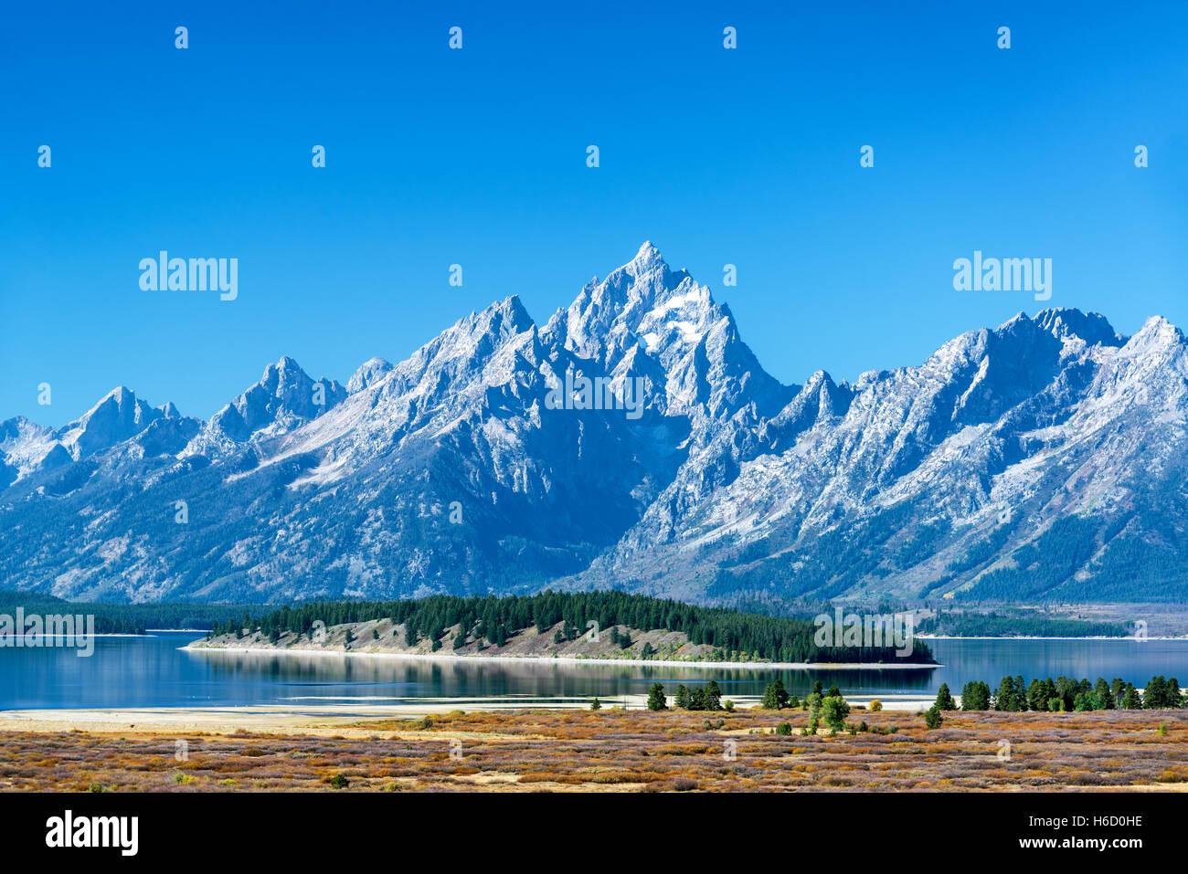 Teton Range with a tree covered island in the middle of Jackson Lake in Grand Teton National Park Stock Photo