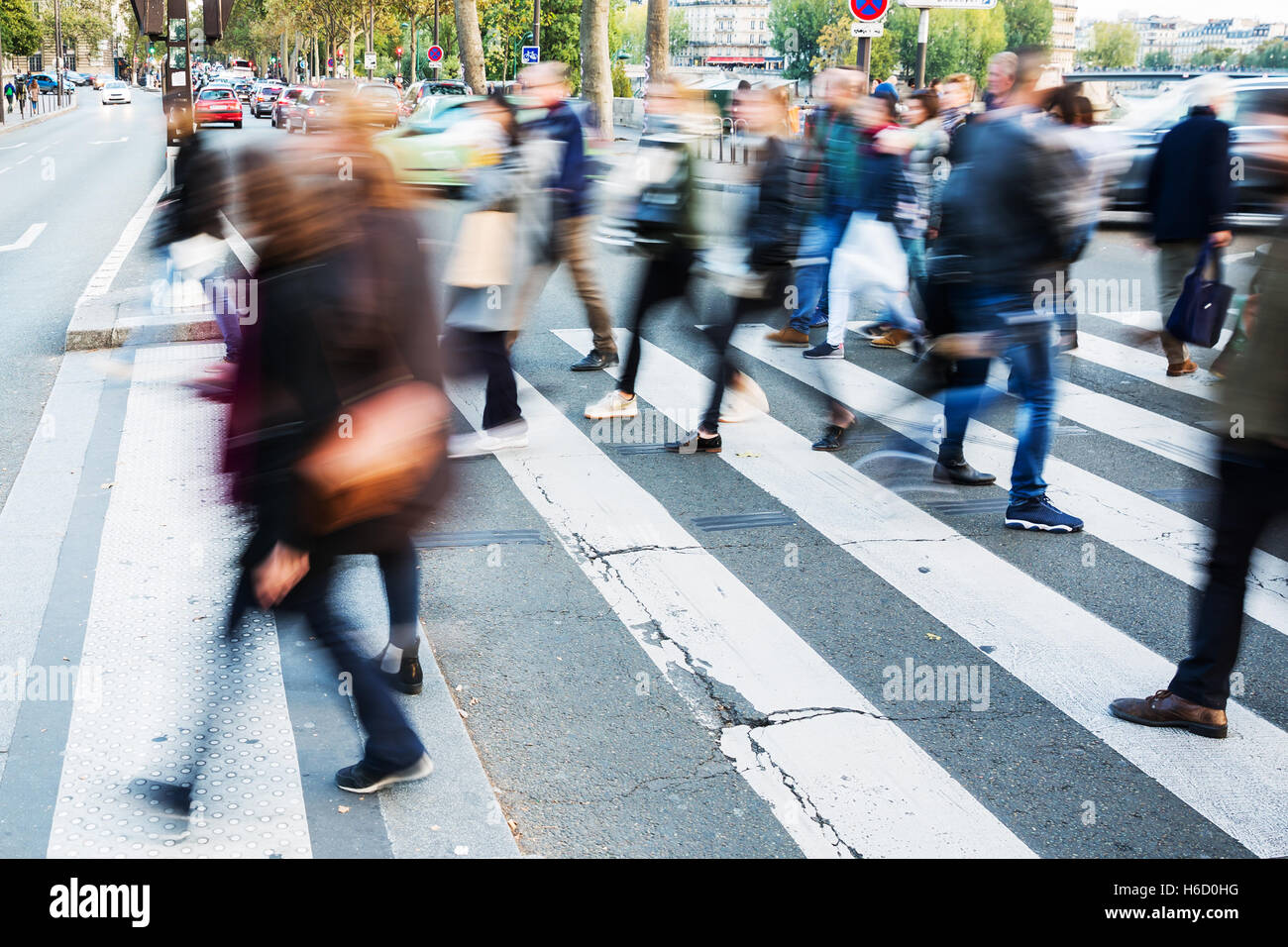 picture with motion blur of a crowd of people crossing a city street at ...