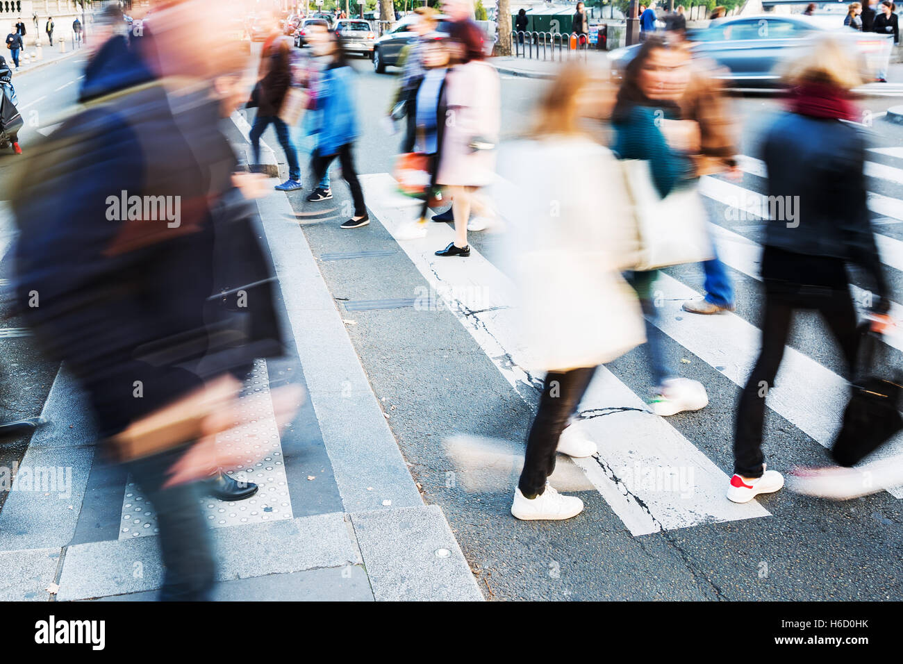 picture with motion blur of a crowd of people crossing a city street at ...