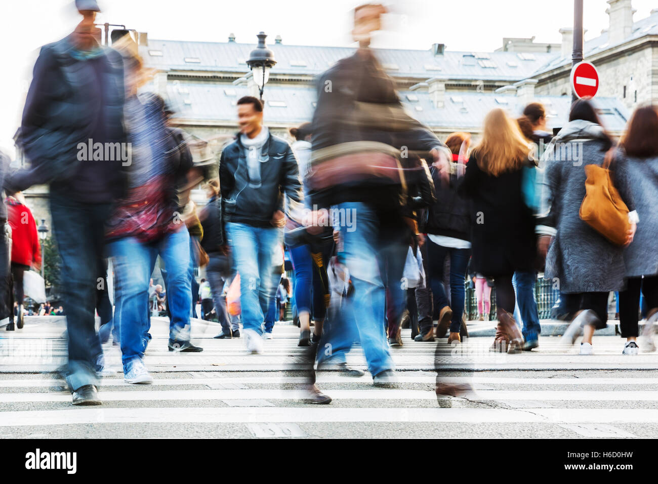 picture with motion blur of a crowd of people crossing a city street at ...
