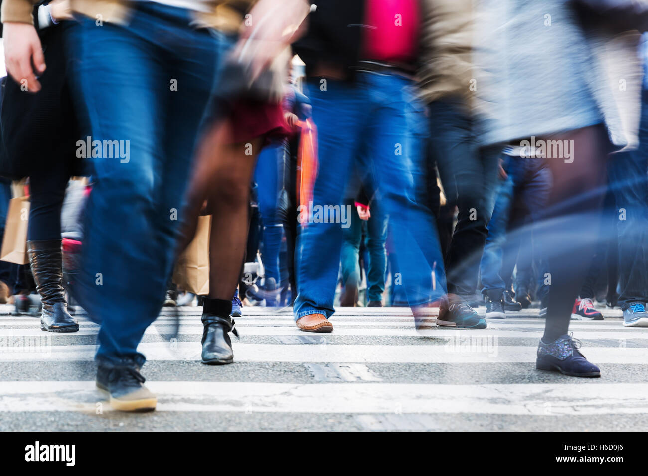 picture with motion blur of a crowd of people crossing a city street at ...