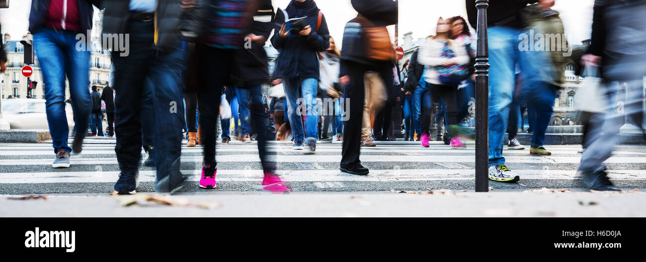 picture with motion blur of a crowd of people crossing a city street at ...