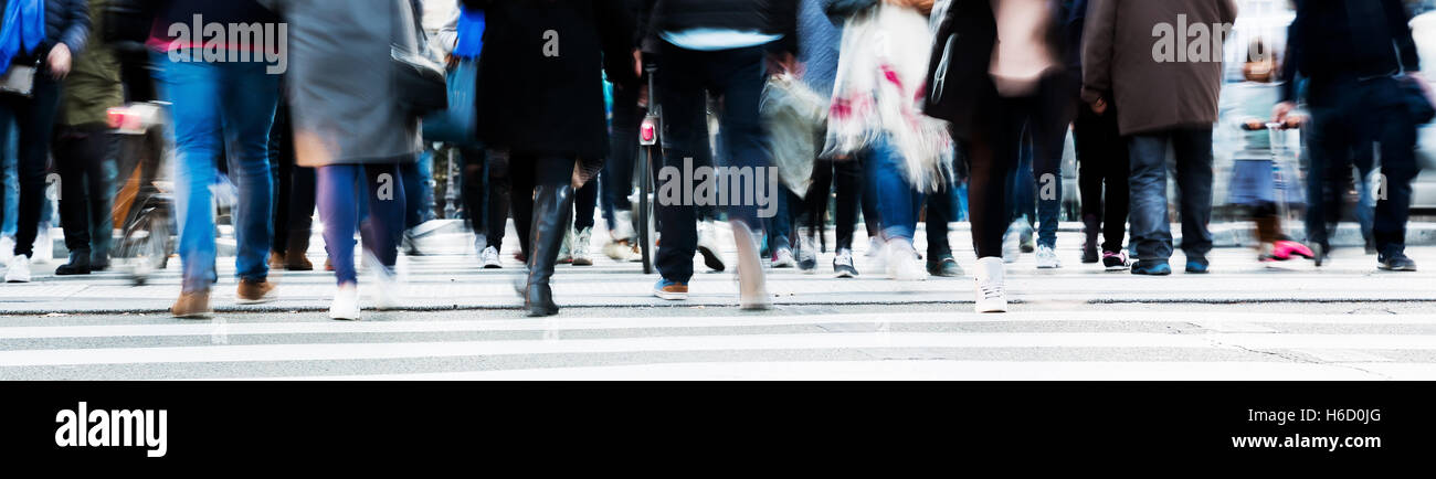 picture with motion blur of a crowd of people crossing a city street at ...
