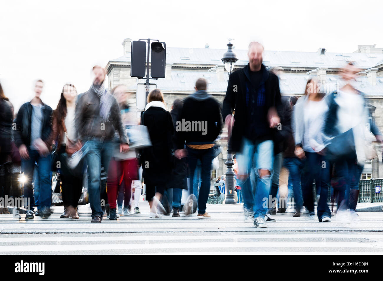 picture with motion blur of a crowd of people crossing a city street at ...