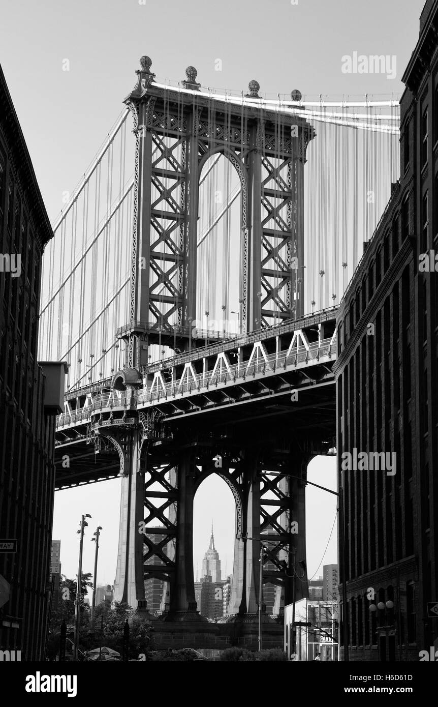 The west pylon of the Manhattan Bridge viewed from Dumbo, Brooklyn, New York.  Empire State Building visible (in B&W). Stock Photo