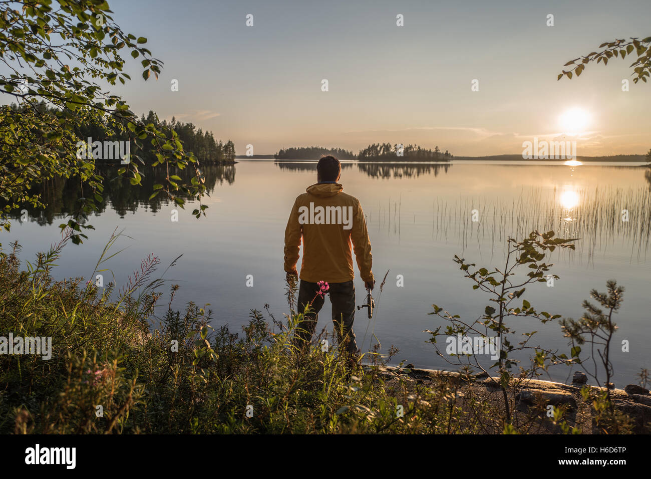 Man is fishing on the sunset lake Stock Photo - Alamy