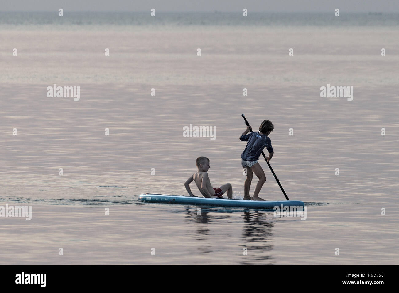 Boys playing on a surfboard, dusk, Kep, Cambodia Stock Photo