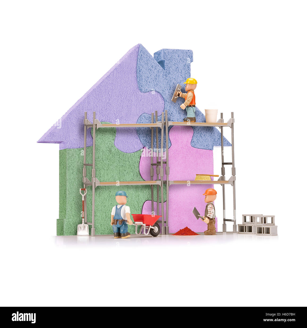 Puppets build a colorful puzzle house, isolated on white. Stock Photo