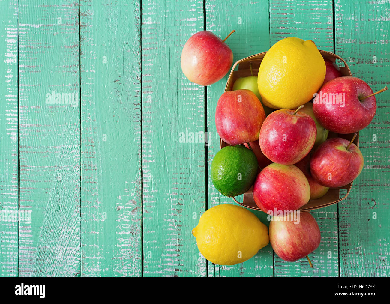 Ripe fruits (apples, lemons and limes) on a bright wooden background ...