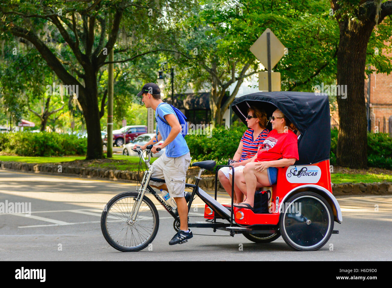 Sightseeing tourists enjoy a pedicab ride  around the historic district of Savannah, GA, USA Stock Photo