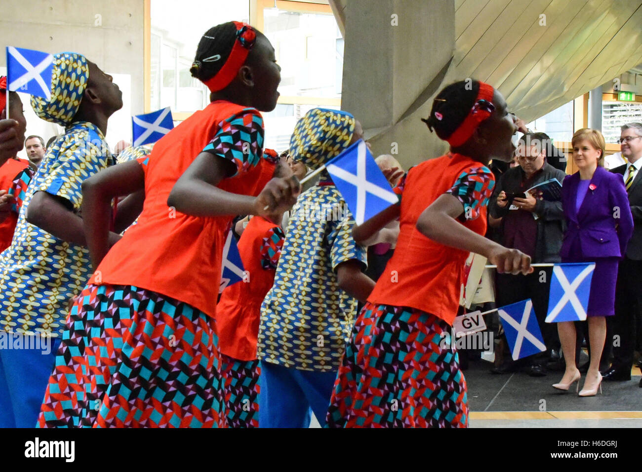 Edinburgh, Scotland, United Kingdom, 27, October, 2016. 'The Singing Children of Africa' choir from Kenya, part of the 'Educate the Kids' charity, wave saltire flags as they perform in front of First Minister Nicola Sturgeon (R) in the Scottish Parliament, Credit:  Ken Jack / Alamy Live News Stock Photo