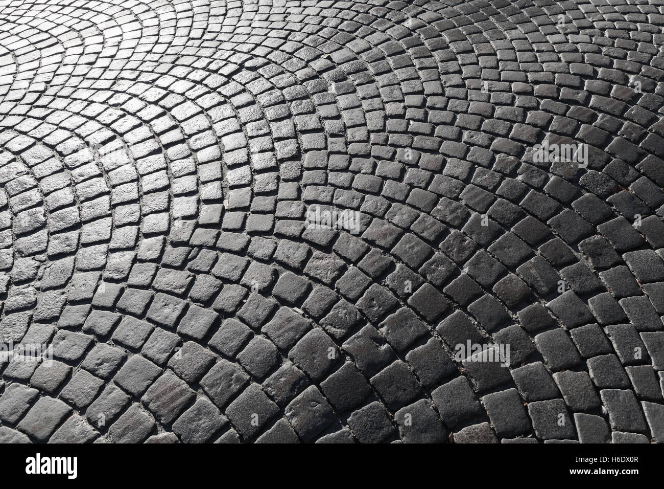Dark shiny cobble road, stone street pavement pattern, background photo texture Stock Photo