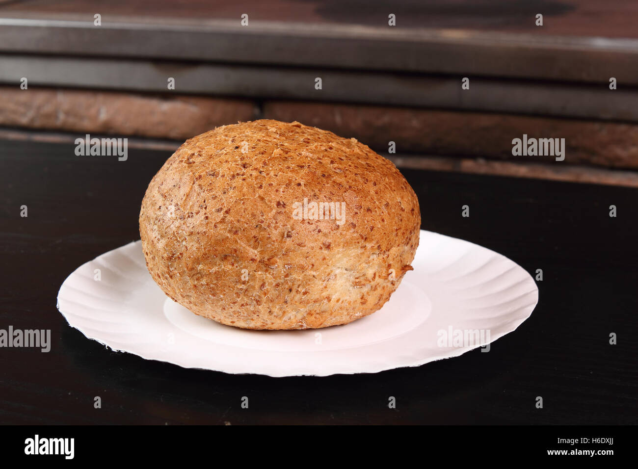 Graham bread roll on paper plate at rural kitchen background Stock