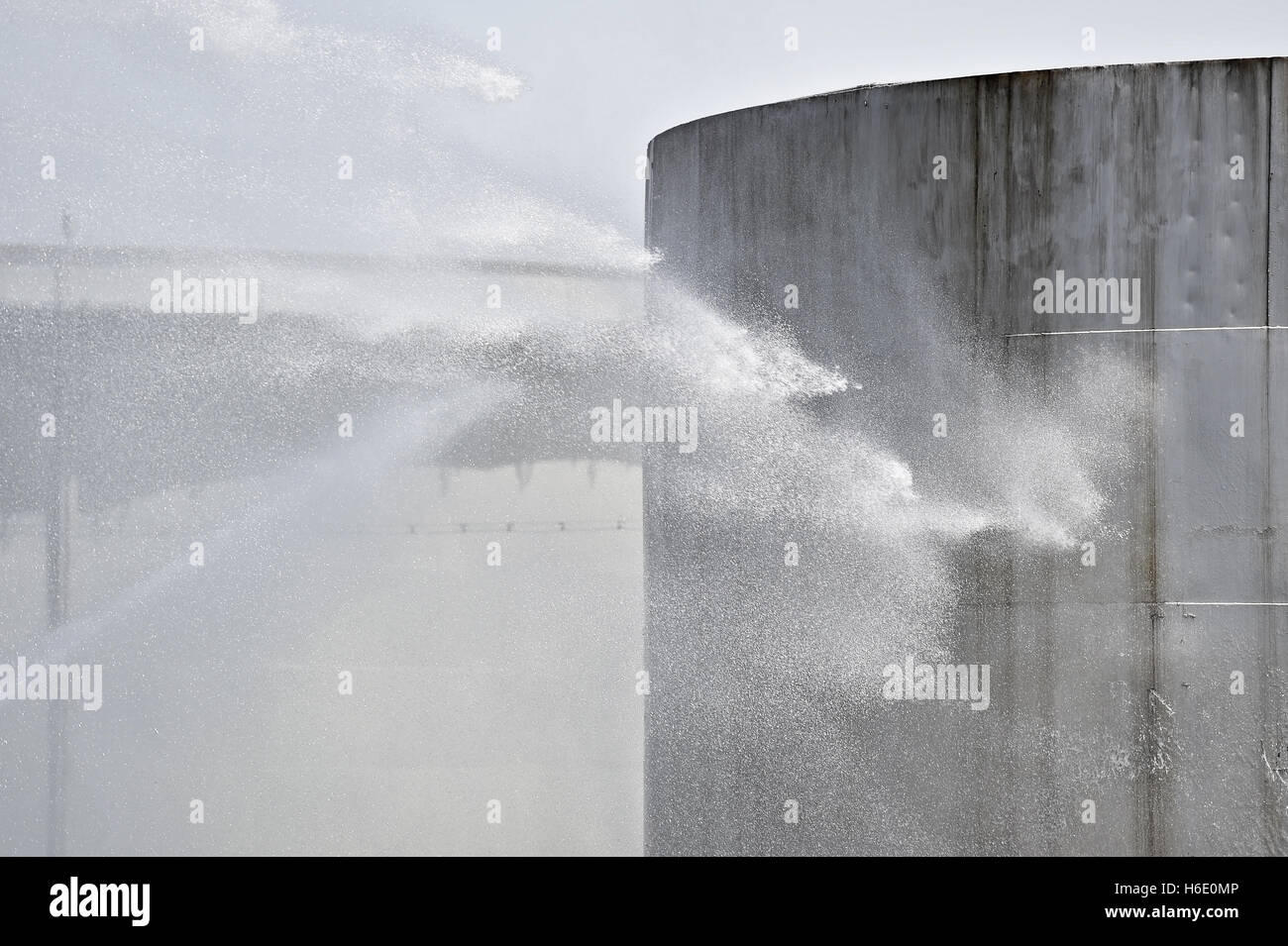 Firefighter water jet extinguish the fire started near a petrol storage tank Stock Photo