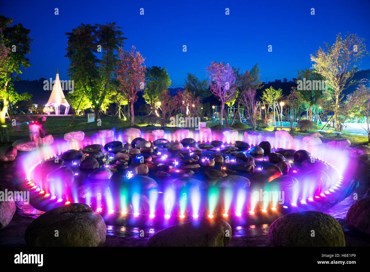 beautiful round fountain with colorful light and stones in park Stock