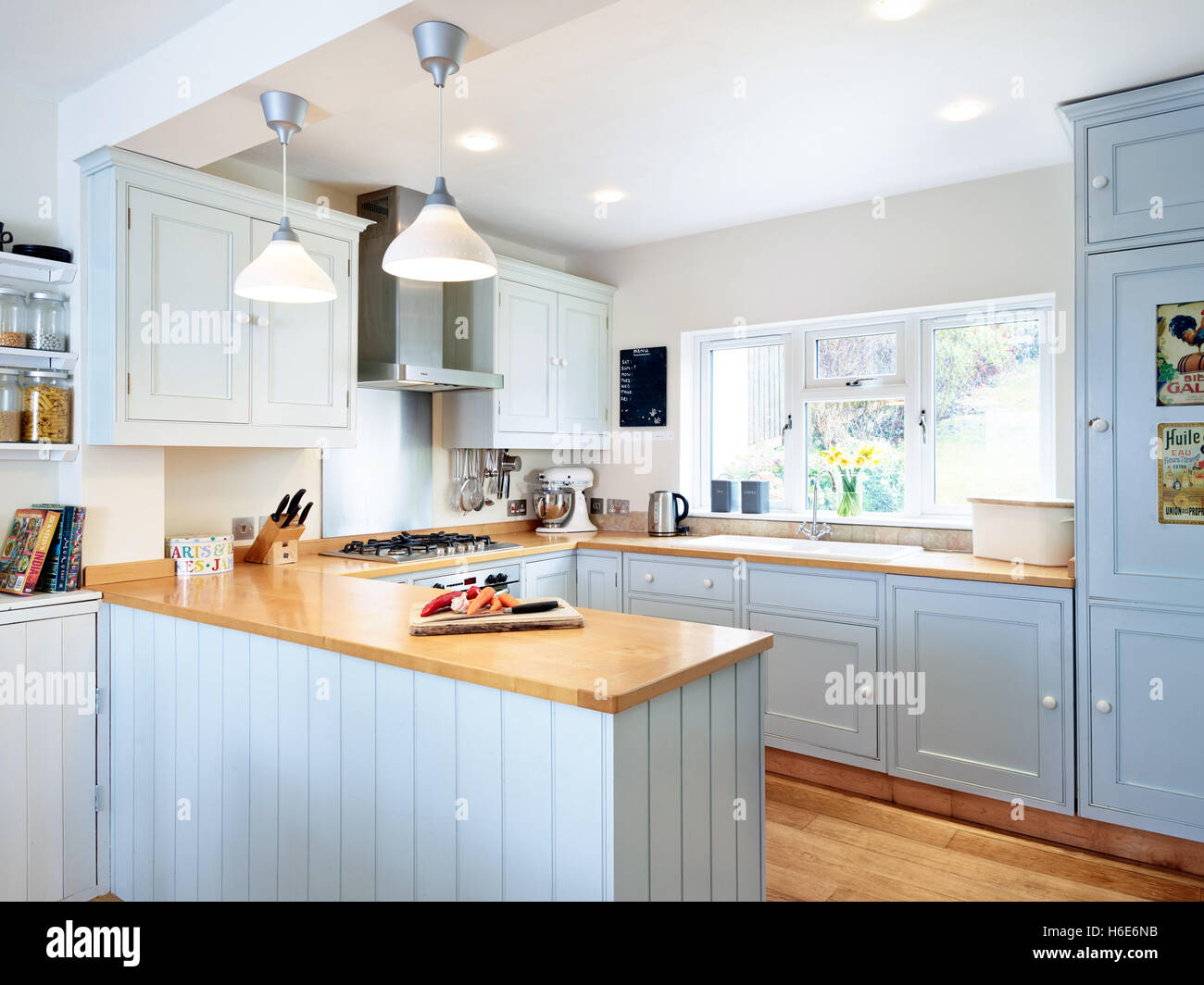 A contemporary, fresh kitchen incorporating an integrated oven, cooker, hood & wood work surfaces. Gloucestershire, UK Stock Photo