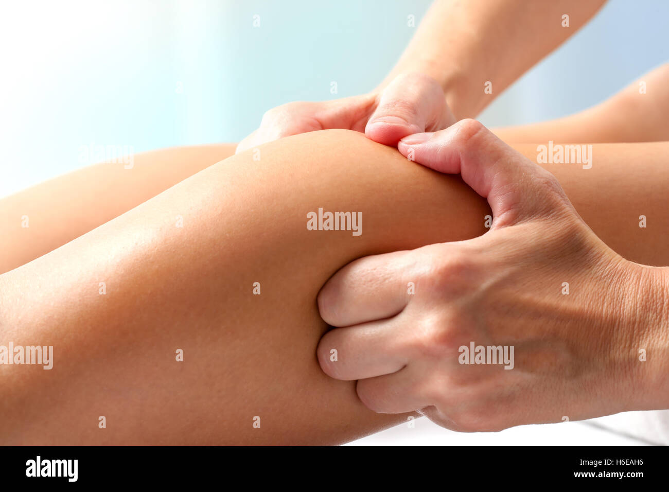 Macro close up of hands doing manipulative healing massage on female calf muscle. Stock Photo