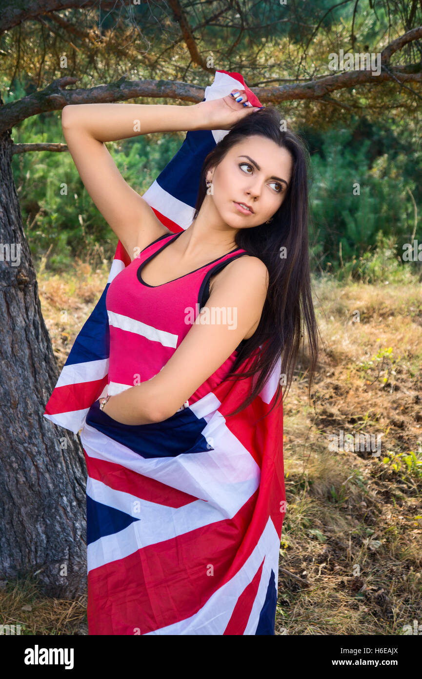 Young beautiful brunette girl posing with a British flag in autumn park Stock Photo