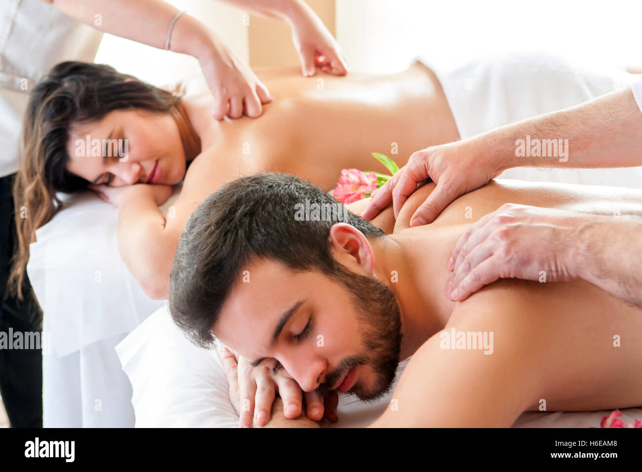 Couple having relaxing body massage in spa.Two therapists doing back massage on couple at the same time. Stock Photo