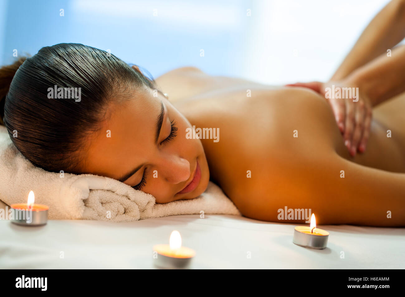 Close up portrait of attractive young woman having relaxing body spa treatment in dim candle light. Stock Photo