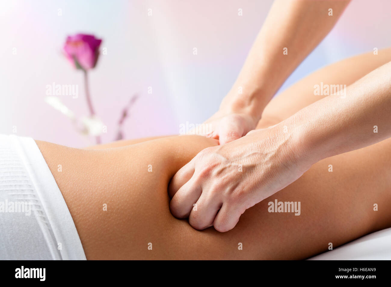 Close up of therapist hands massaging female hamstrings on leg. Stock Photo