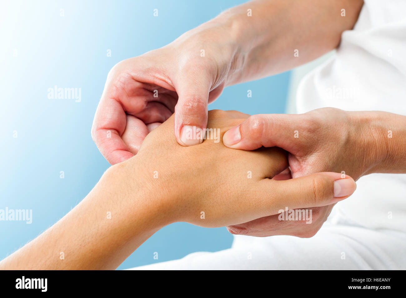 A close-up of a massage therapist's hands applying pressure to a client's muscles, using traditional Latin massage techniques