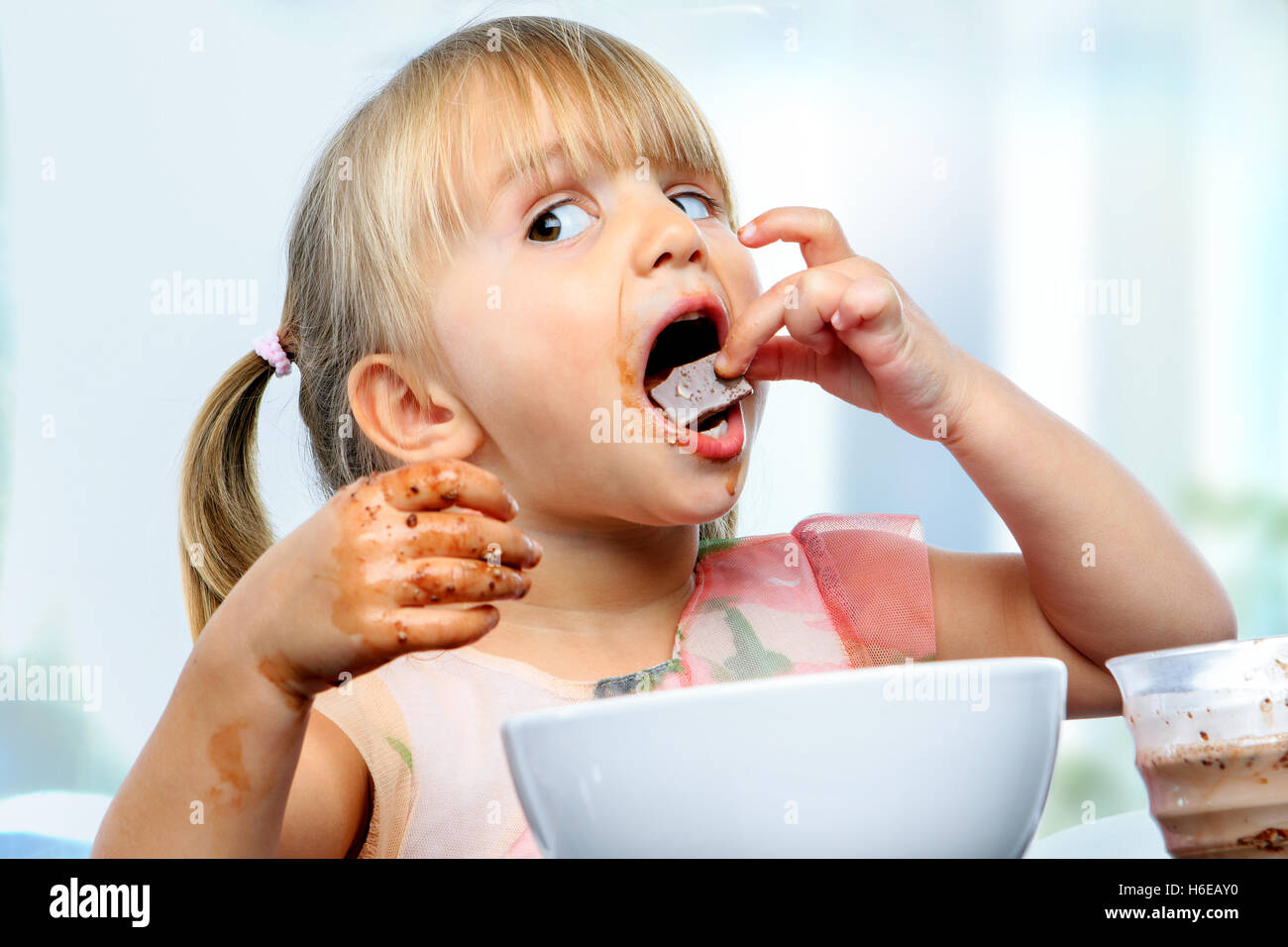 Close up portrait of infant eating and messing with chocolate at breakfast. Stock Photo