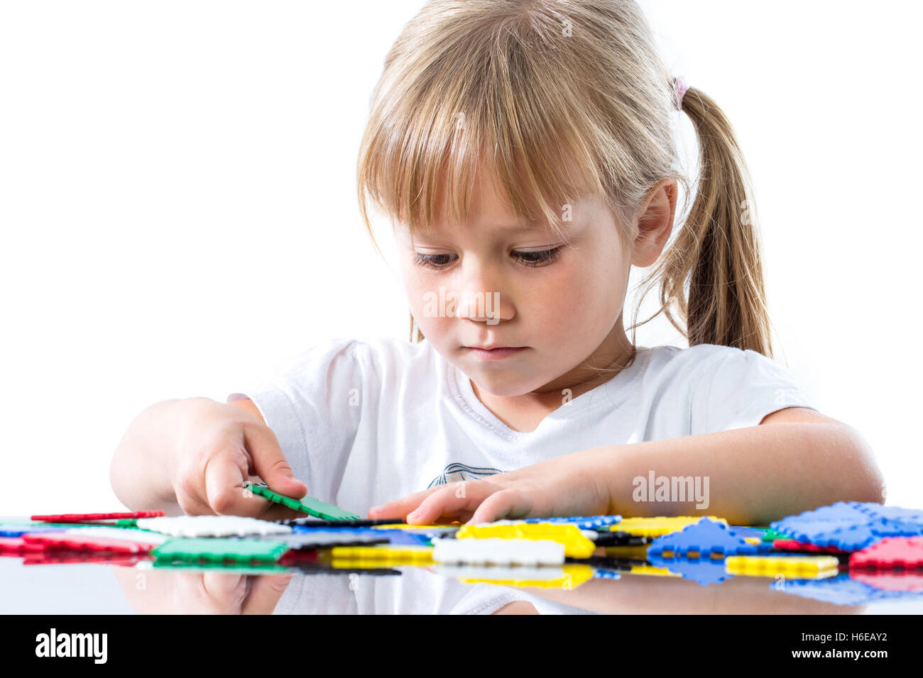 Close up portrait of cute little girl playing with puzzle pieces at ...