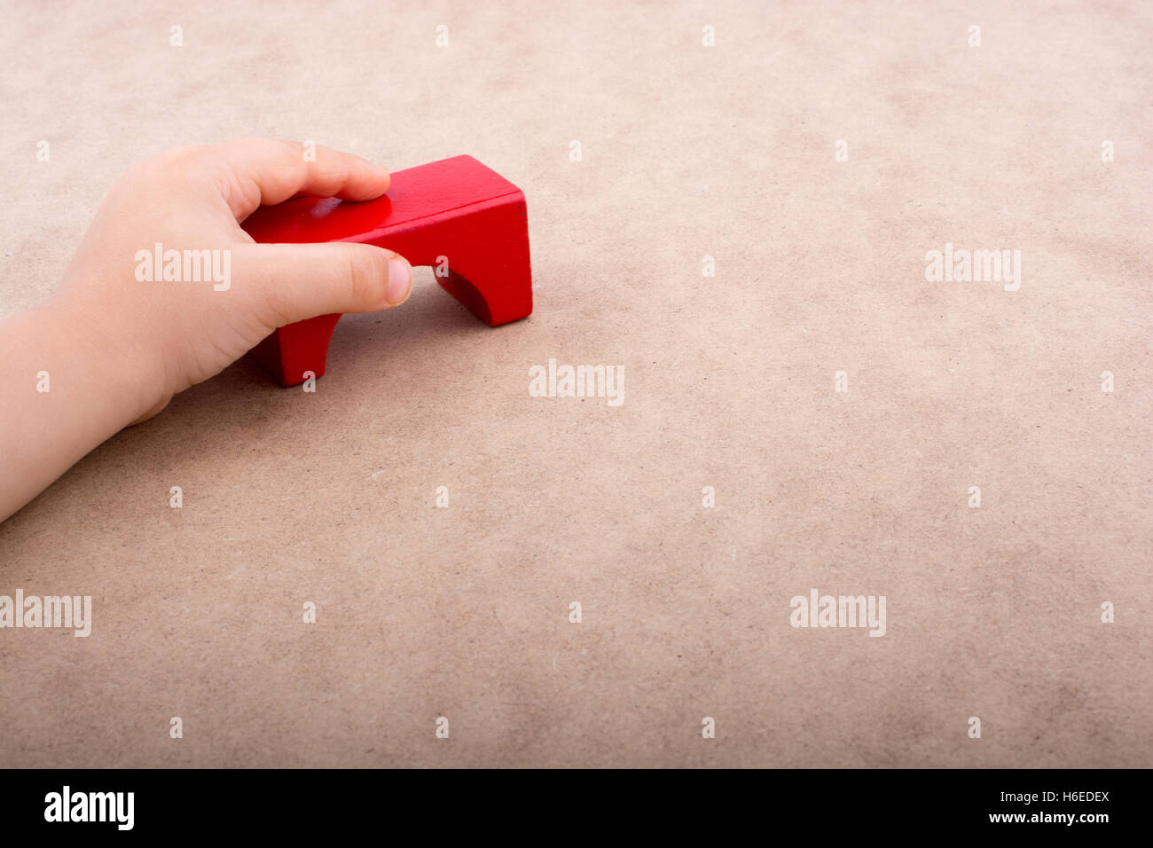 Hand holding a red building block on a white background Stock Photo - Alamy