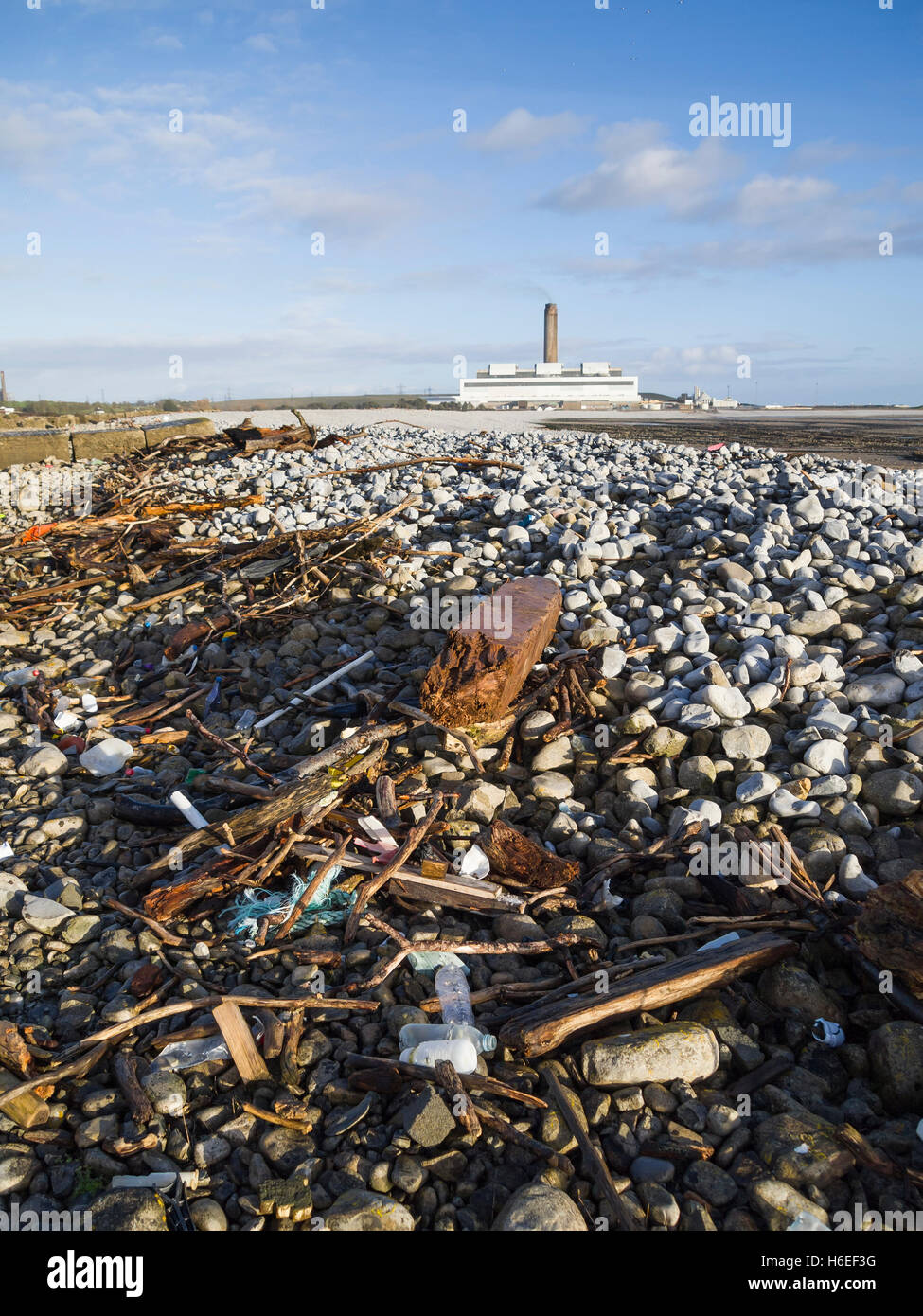 driftwood and trash washed up on  beach power station in background Stock Photo