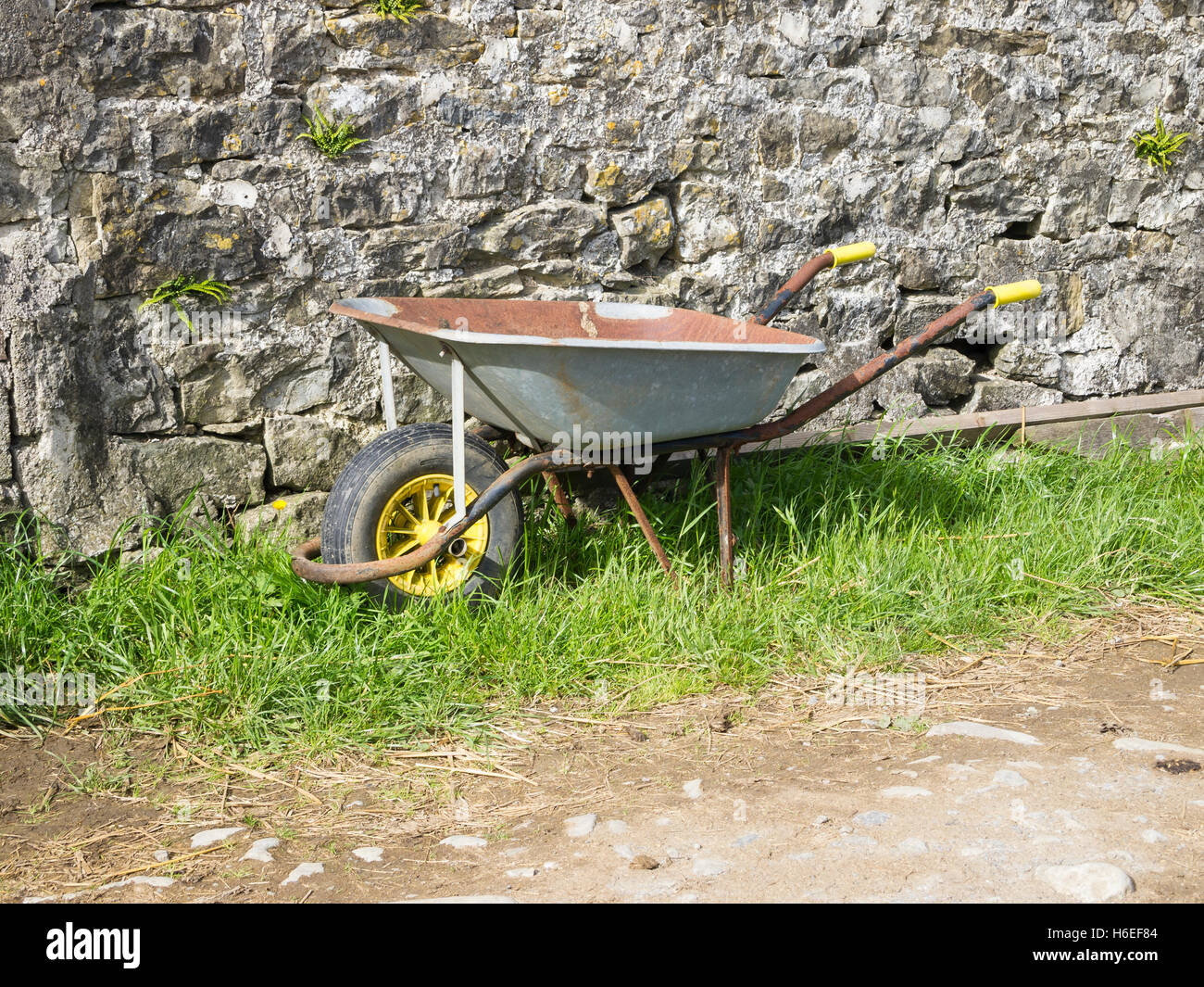 wheelbarrows by rural stone wall outside stables Stock Photo