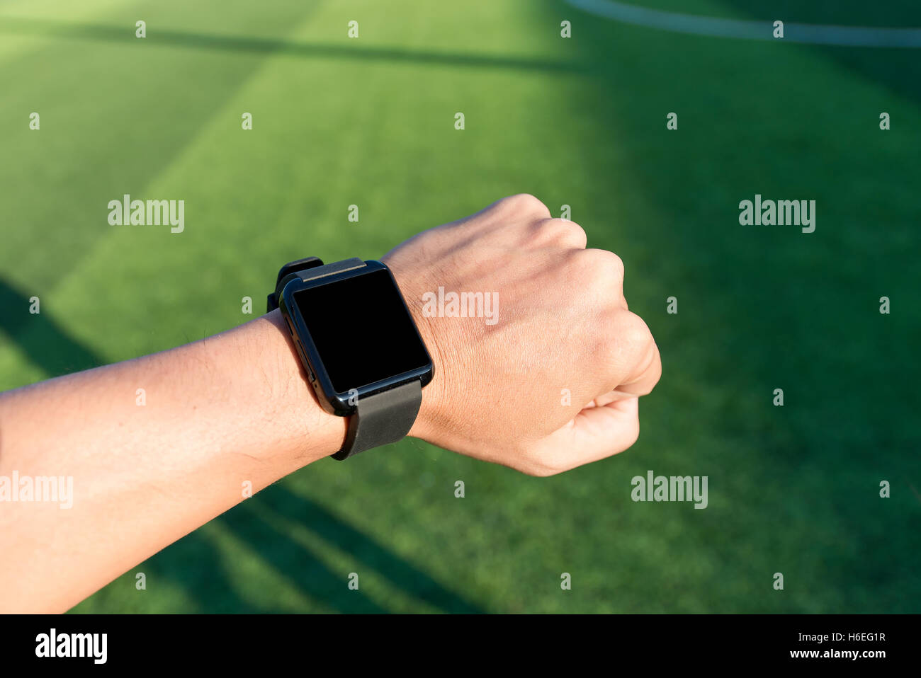 Closeup hands of man using his smart watch exercise in soccer field