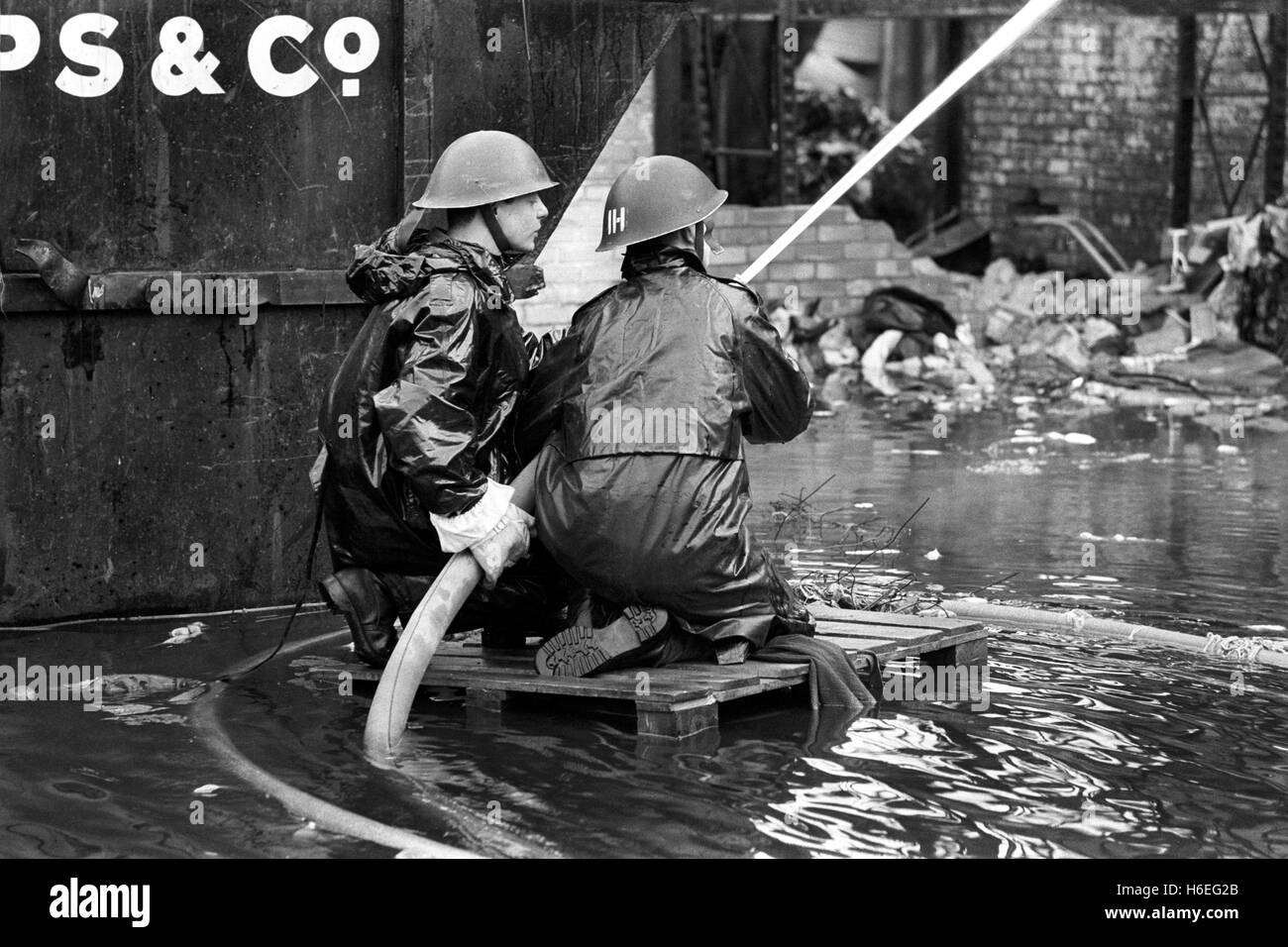 Army firefighters on a 'raft' surrounded by water as they direct a hose at a building involved in what was said to be the biggest blaze in London since the start of the firemen strike. The fire - at C and N Rags Ltd in Stratford, London, spread through five factory blocks in an industrial estate. Stock Photo