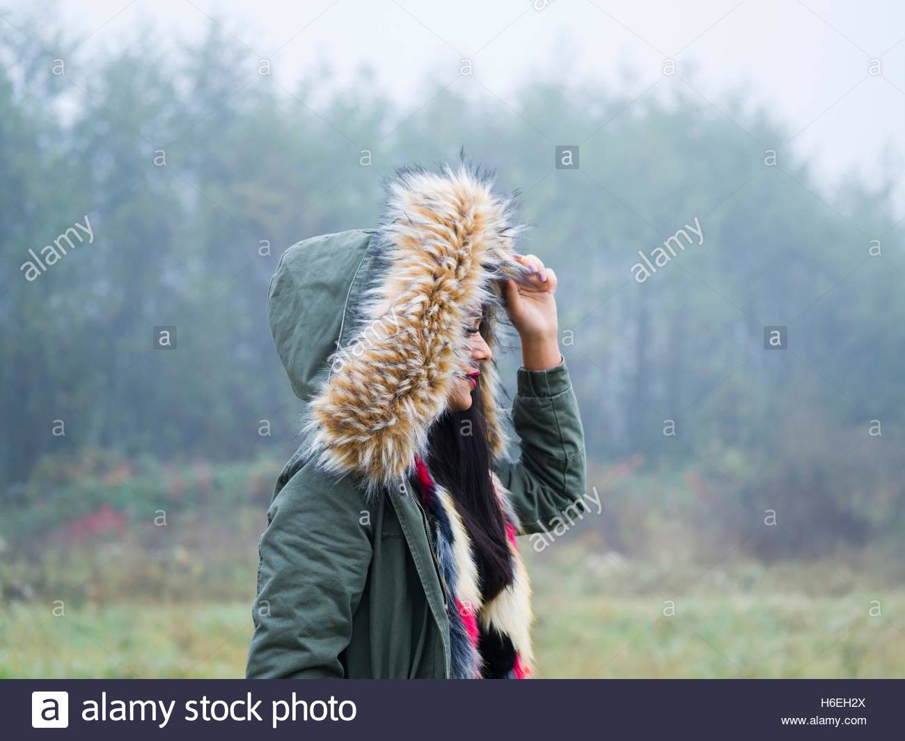 Under hood cold weather walking walk girl outdoors foggy day side view forest in nature hoodie single Stock Photo