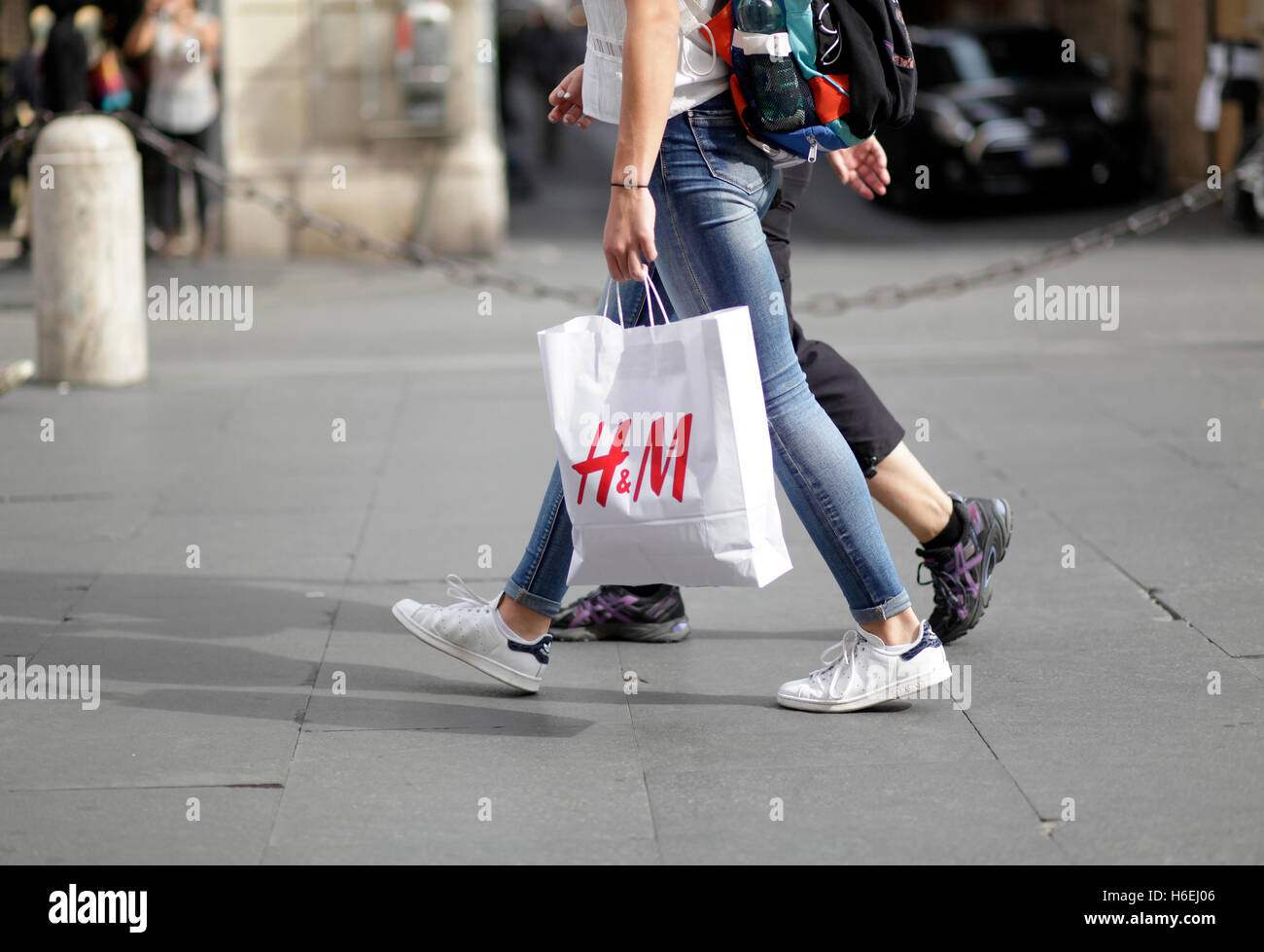 Pedestrian walks with her H&M shopping bag on Via del Corso, main shopping street in Rome, Italy Stock Photo