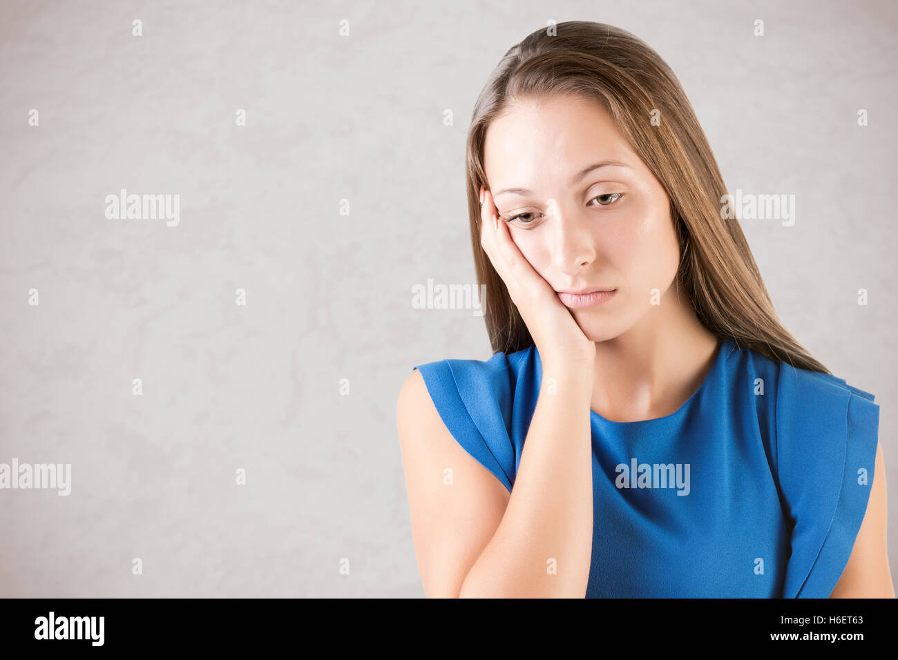 Sad and bored woman thinking about something, isolated in grey Stock Photo