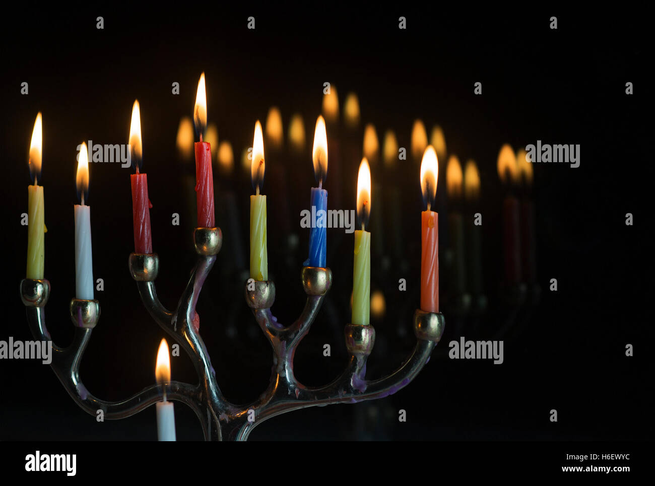 Menorah with all candles lit and reflections in glass window on last