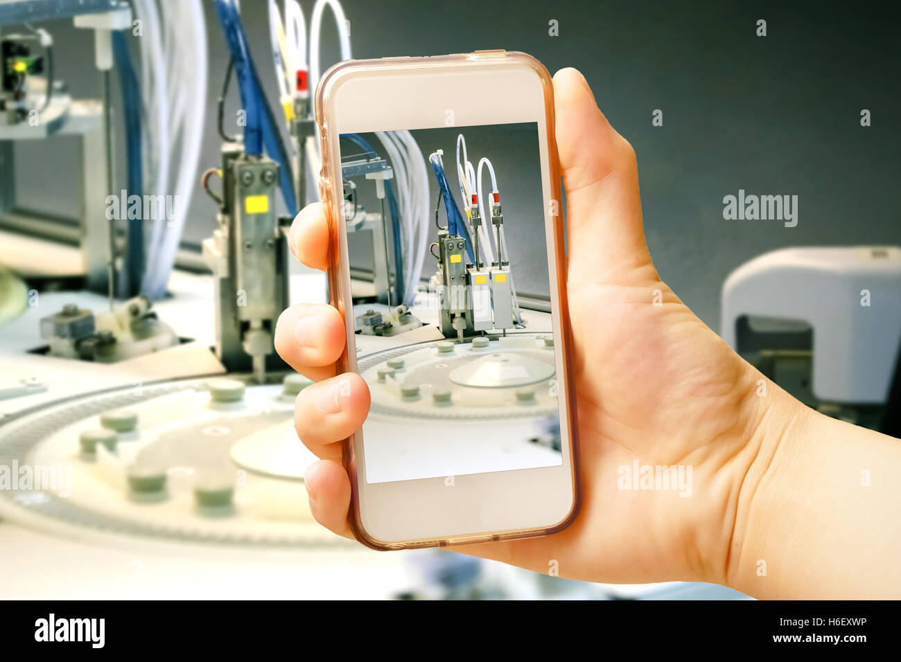 Hand holding smart phone (Mobile Phone) with centrifuge. advanced laboratory equipment Stock Photo