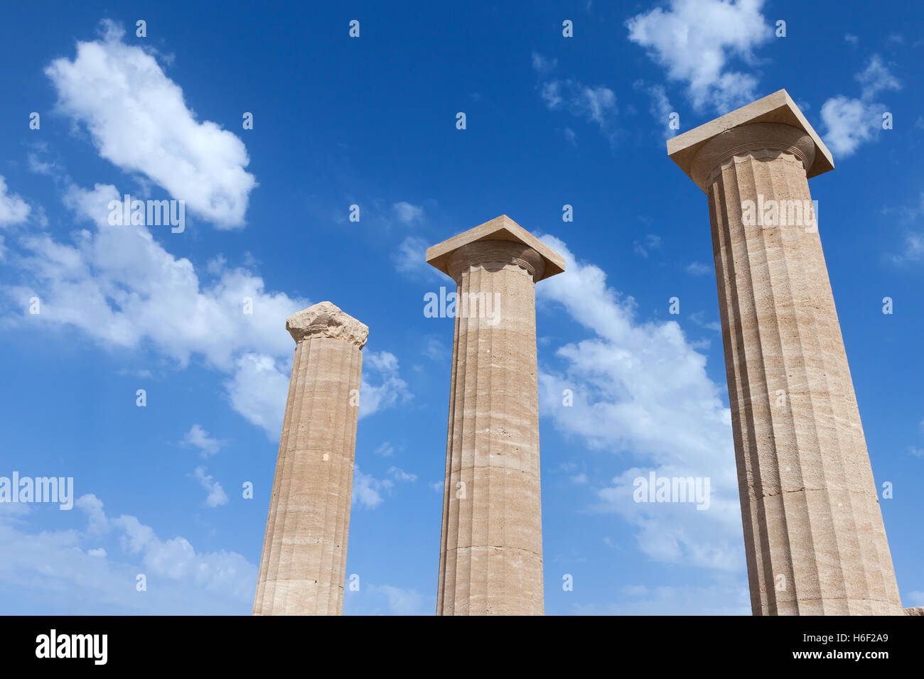 Ancient Greek pillars at the Athens acropolis with blue cloudy sky in