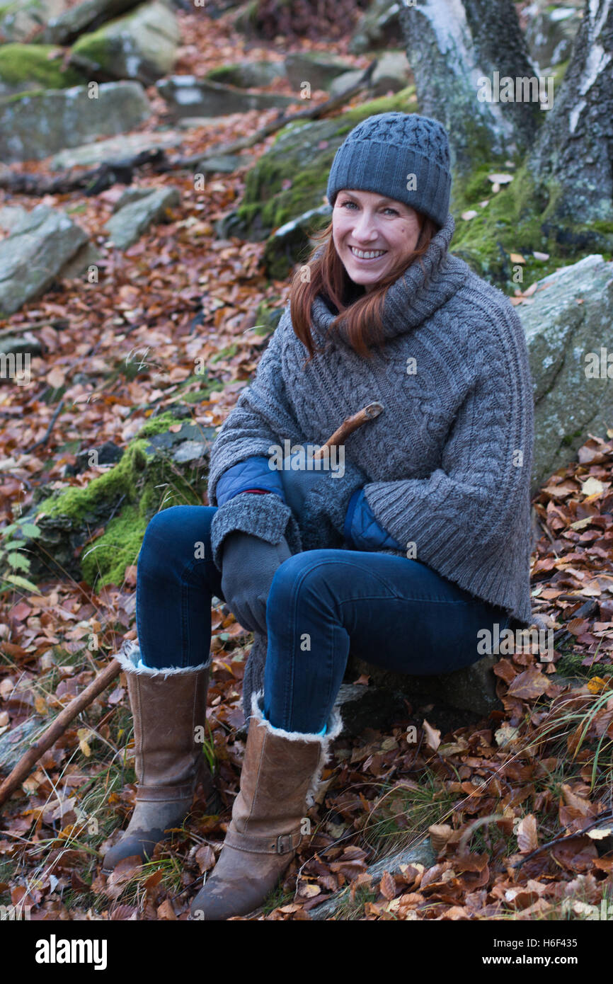 A glamourous woman hiking through the woods in autumn fall season wearing a  casual wool poncho leisure wear woolly hat boots Stock Photo - Alamy