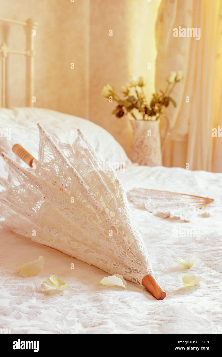 Lace parasol on the bed with wedding dress in the background Stock Photo