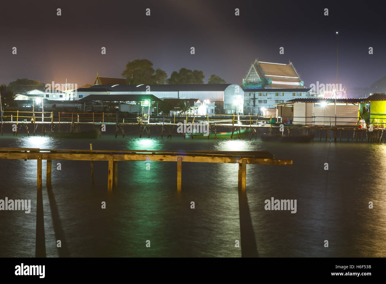 wooden house and wooden bridge on the sea at night with color light ...