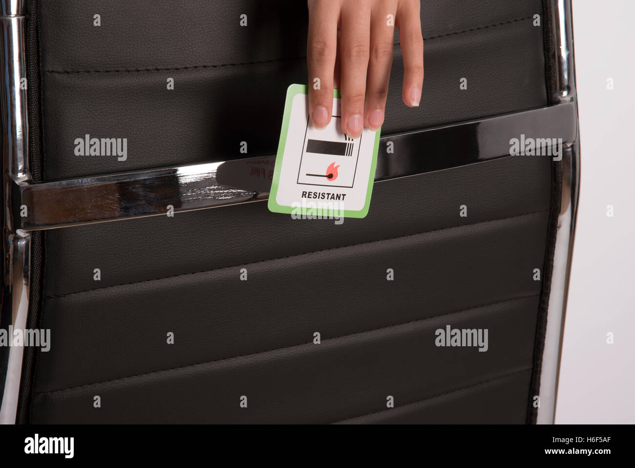 Label on furniture - Certification label indicating that the leather office chair is fire resistant being held in a woman's hand Stock Photo