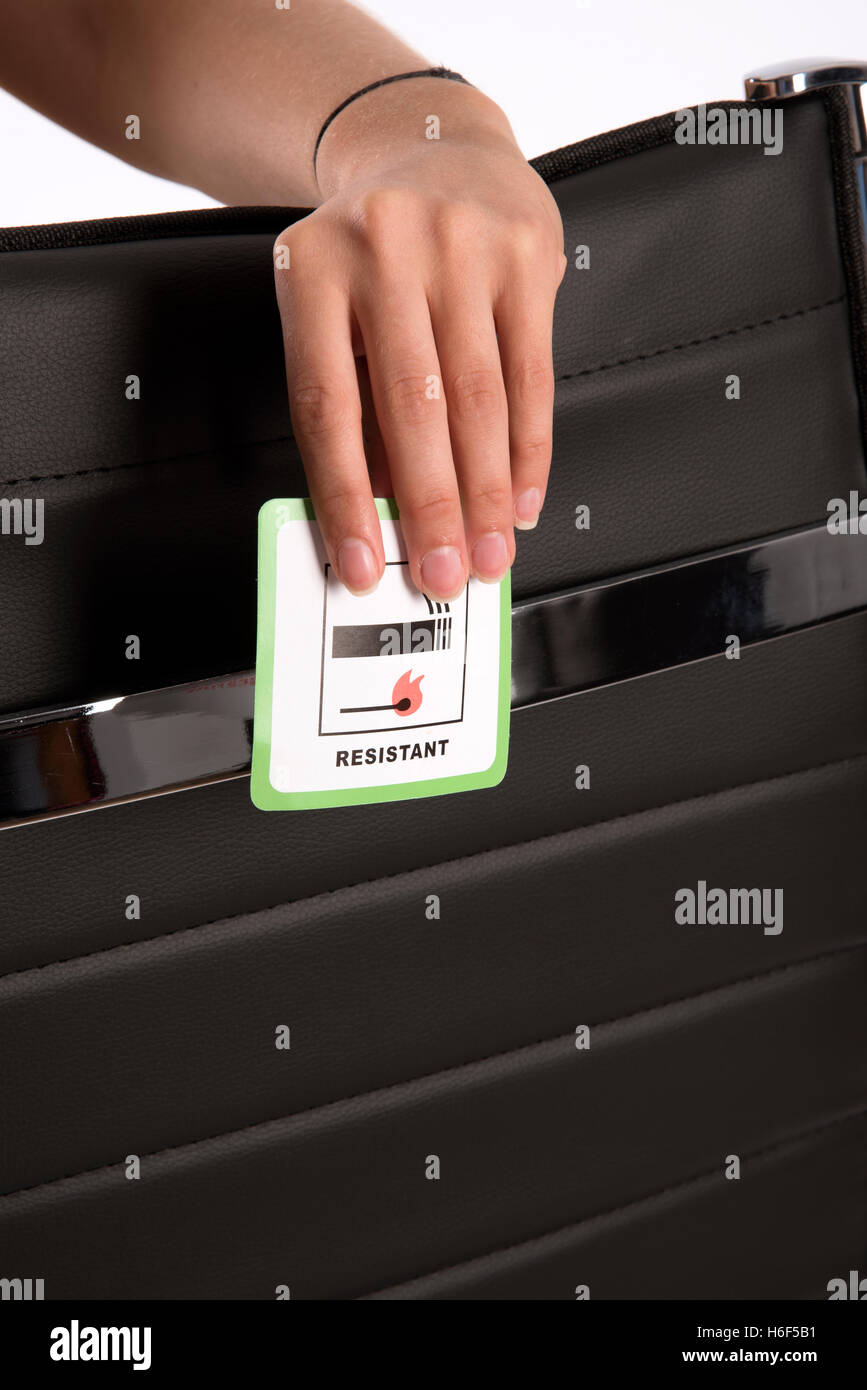 Label on furniture - Certification label indicating that the leather office chair is fire resistant being held in a woman's hand Stock Photo